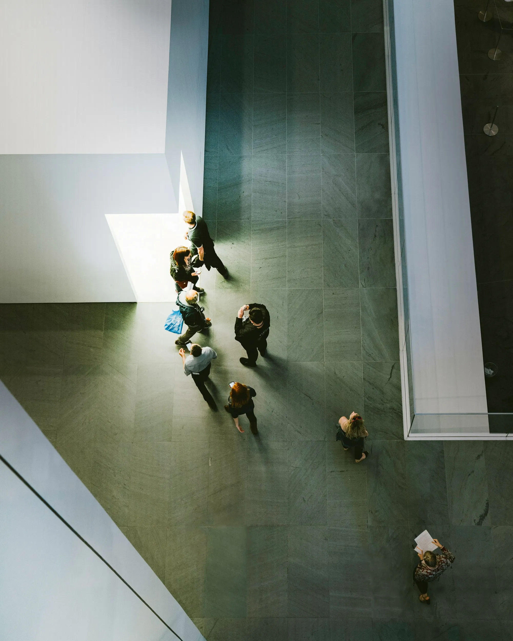 Besucherinnen und Besucher in der lichten Halle eines Museums, von oben gesehen